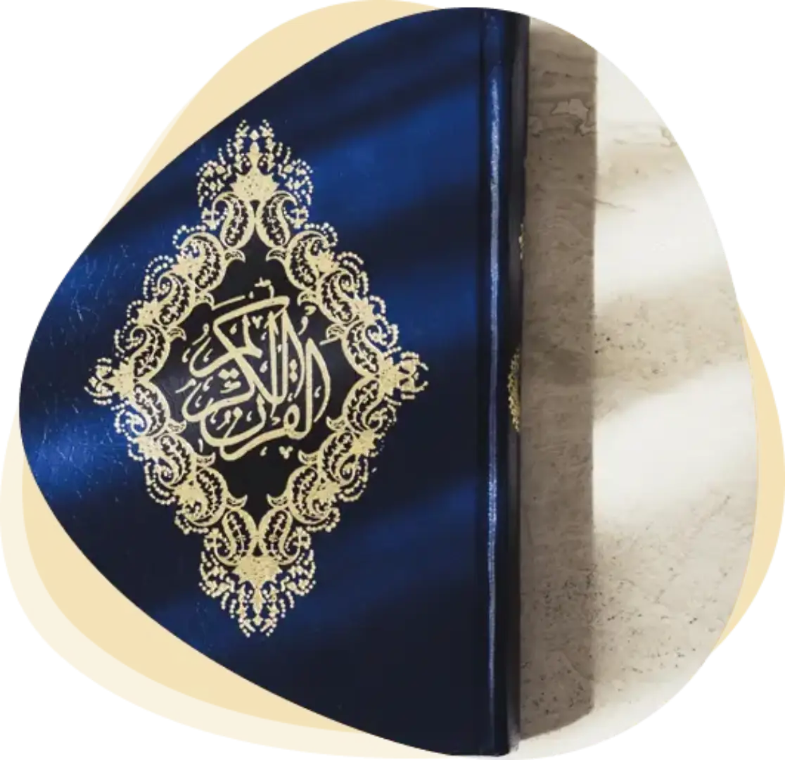Blue Quran with golden Arabic calligraphy cover placed on marble surface – About The Orbit Quran Academy