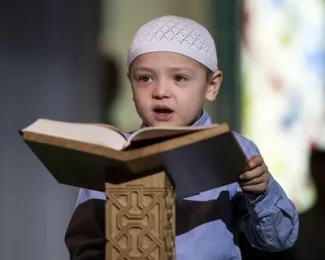 Child reciting Quran from rehal in mosque, highlighting Islamic education and spiritual growth Online Quran Courses