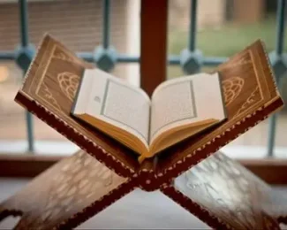 Open Quran on wooden rehal near window, symbolizing Islamic study and spiritual reflection Online Quran Courses